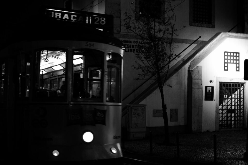 A yellow number 28 tram climbing a narrow street in Lisbon's Alfama district