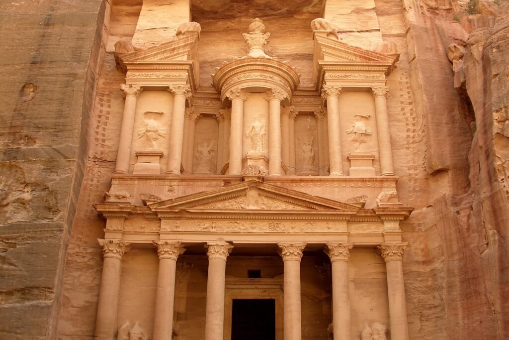 The carved sandstone facade of the Treasury at Petra seen from the end of the Siq