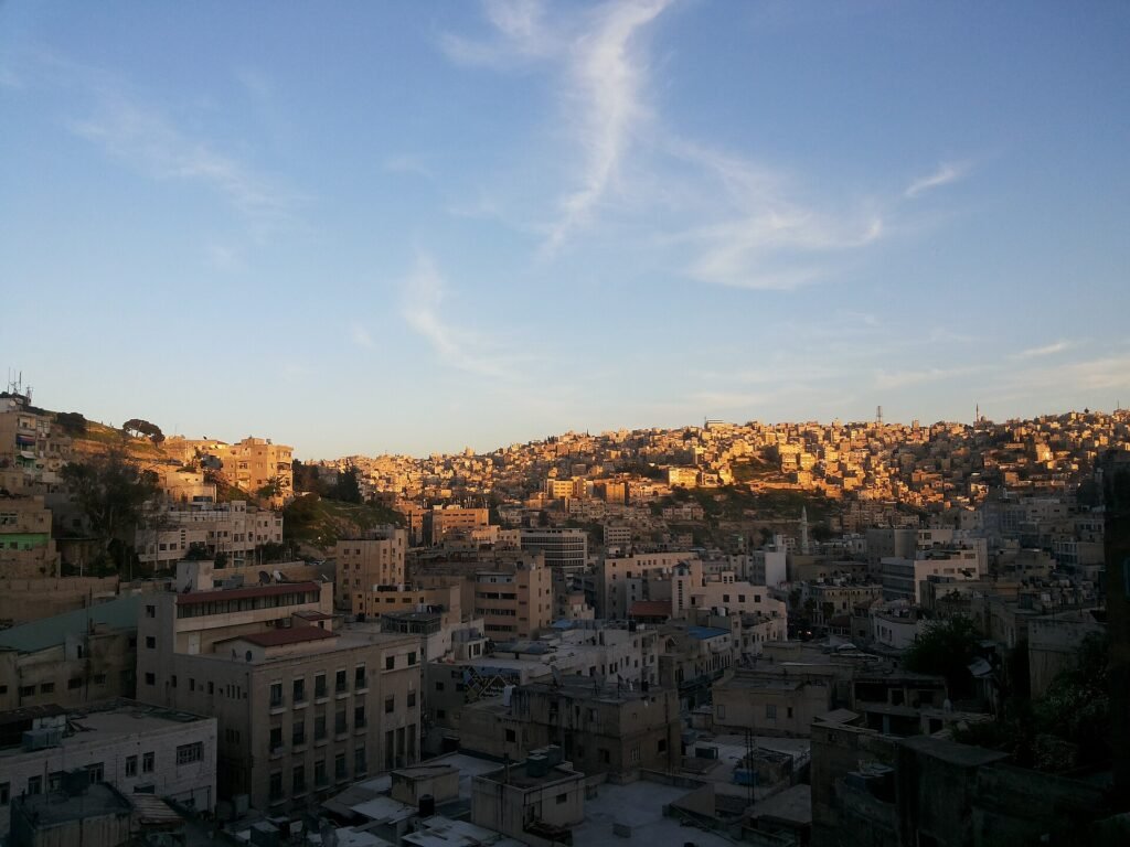 Busy street and market stalls in downtown Amman with hillside houses behind