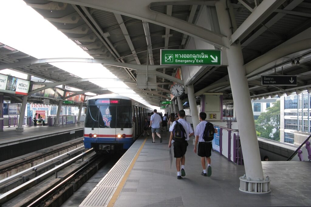 A BTS Skytrain arriving at an elevated station in central Bangkok